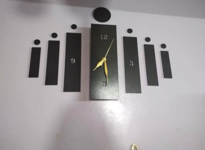 Black slot-style wall clock mounted on a light wall