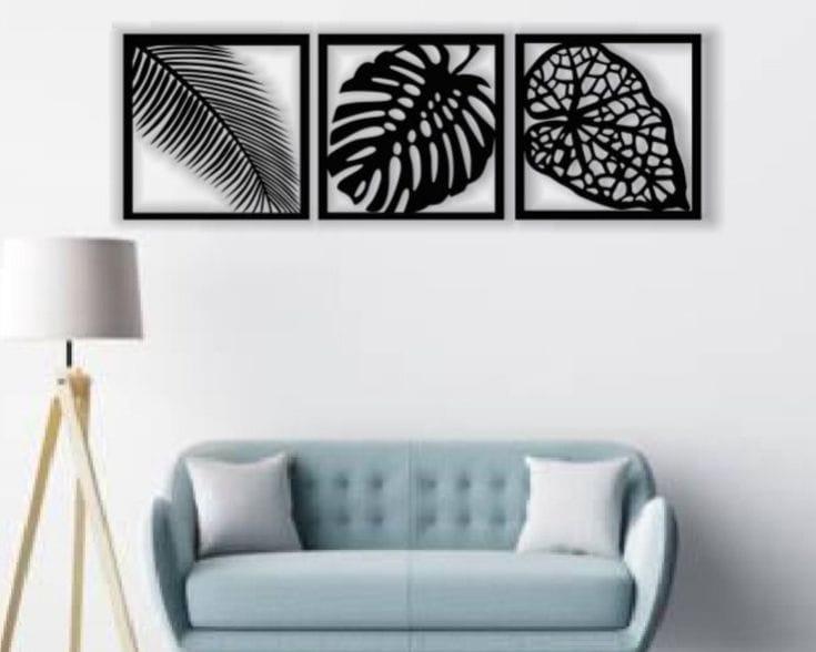 Three black leaf wall art frames above a wooden console