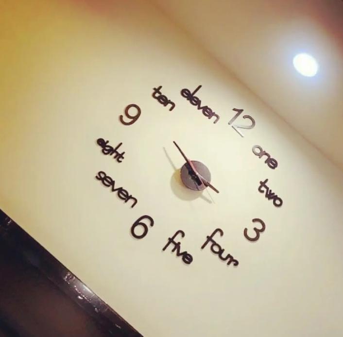 Black 3D wall clock displayed on a light wall