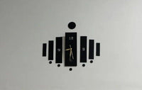 Black wooden wall clock with central hands and surrounding decorative panels