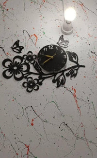 Black flower and butterfly wall clock on patterned wall