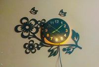 Front view of black flower and butterfly wooden wall clock with warm LED light
