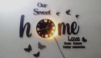 Close-up of black Our Sweet Home wall clock with butterfly and bird details